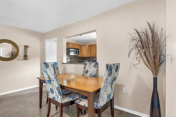 Kitchen with wood cabinetry, granite countertops, stainless steel appliances, and a double sink beneath a window. Includes a breakfast bar with seating and tile flooring.