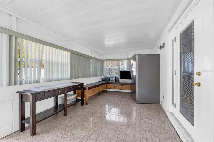 Sunroom with tile flooring, vertical blinds, storage benches, and refrigerator