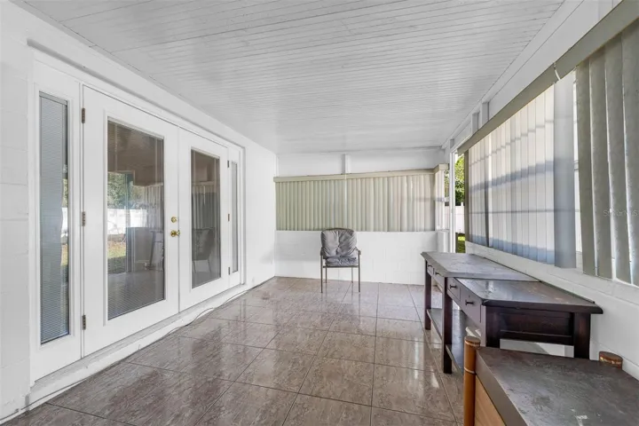 Enclosed patio with tile flooring, French doors, and large windows.