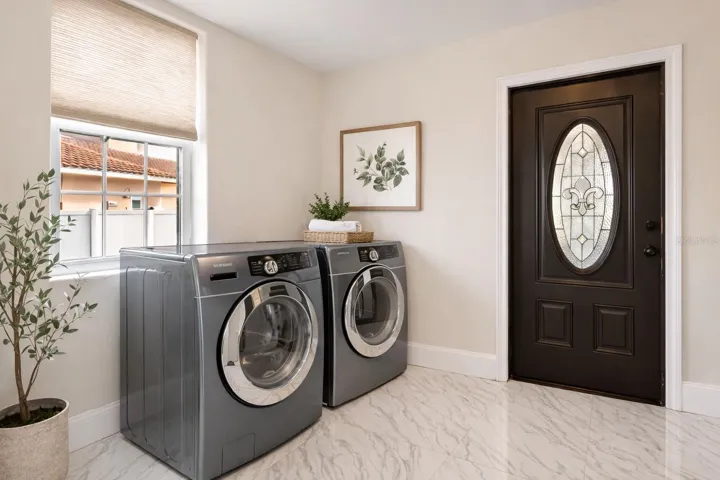 Downstair laundry, located off garage - Virtual staging added to demonstrate possible furniture placement.