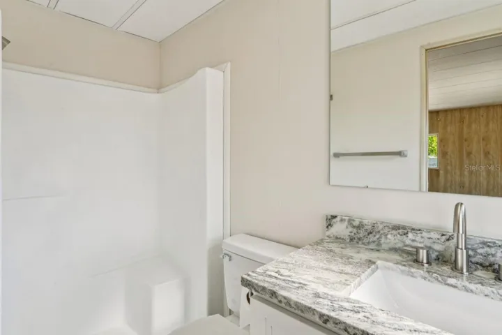primary walk in shower granite vanity wood cabinet