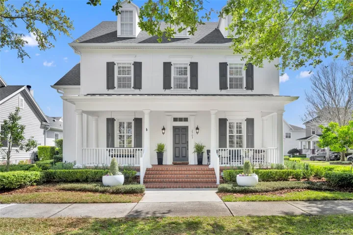 Classic Colonial-style exterior featuring an inviting covered front porch, brick steps, and a welcoming entry