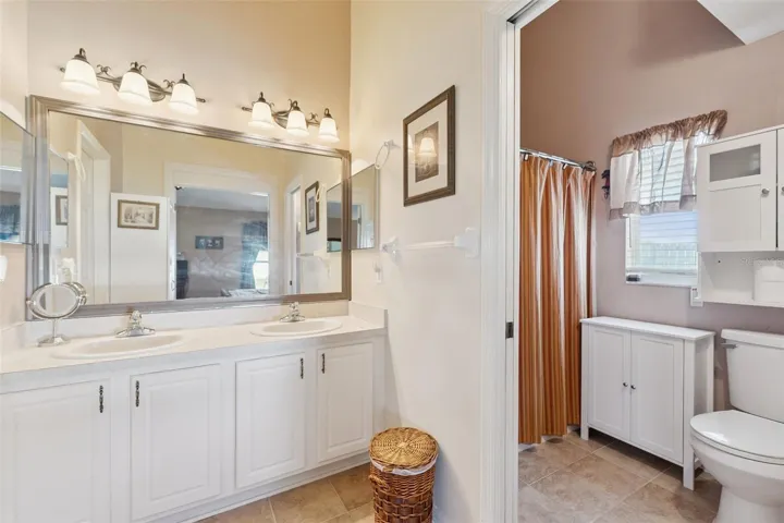 Primary Bathroom features dual sinks, linen closet and pocket doors leading into the water closet