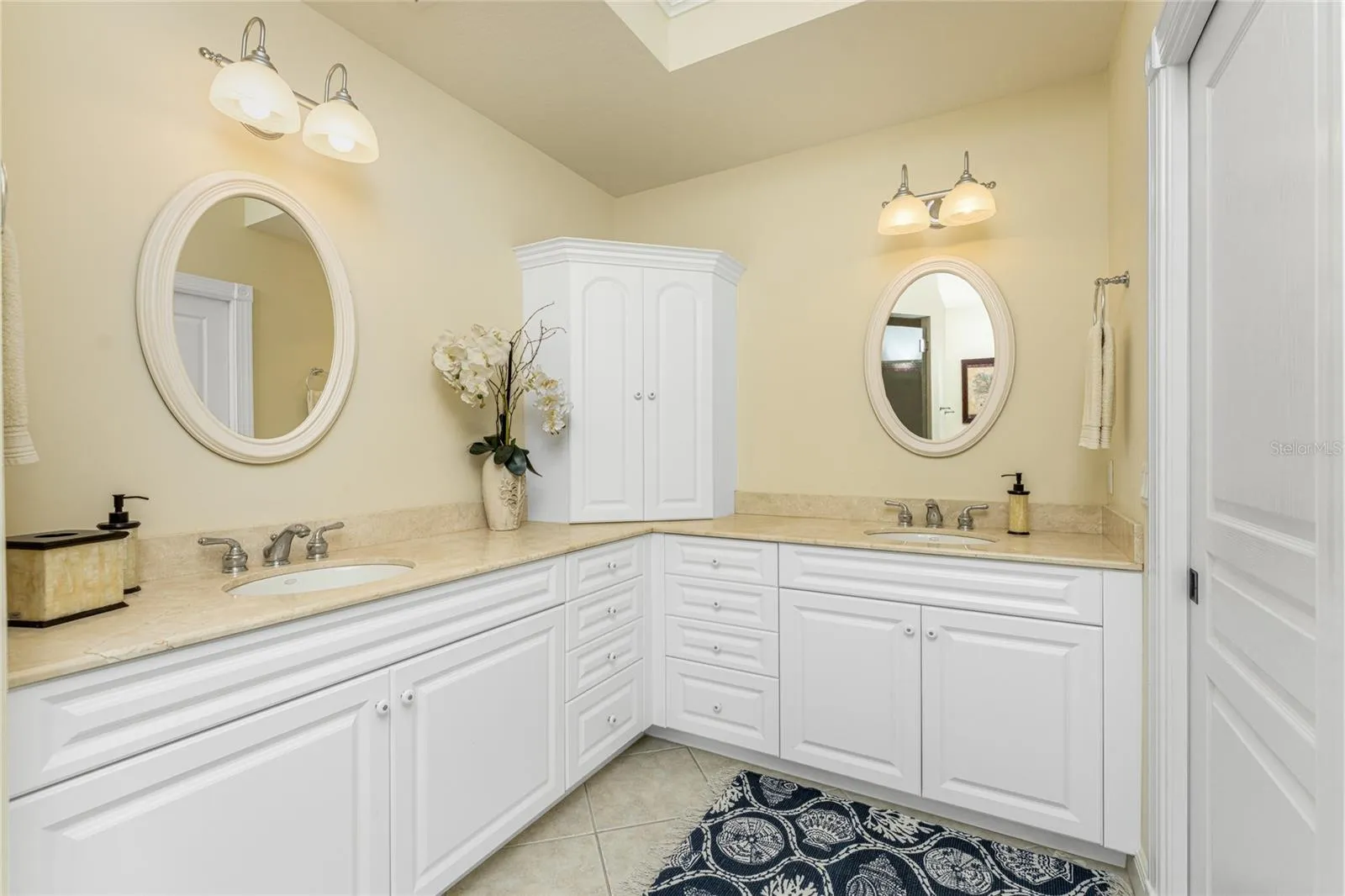 Double vanities, crema marfil marble tile, and endless counter space — elegance and ease,