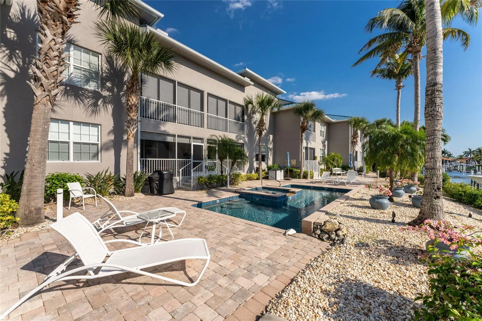 Where every day feels like a resort — a sun-soaked paver pool deck, heated pool, and built-in hot tub, all steps from the waterway and surrounded by swaying palms and blue Florida skies.