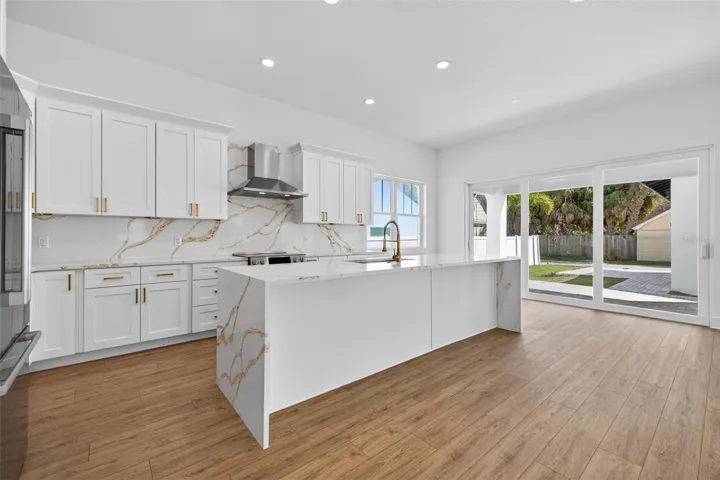Generous kitchen with waterfall quartz countertop island.