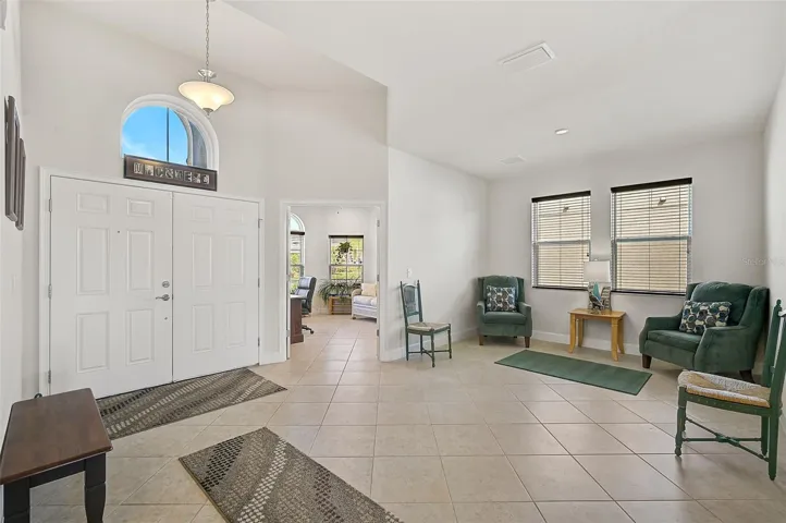 Open foyer with formal sitting area and double doors entering into a home office/den or library