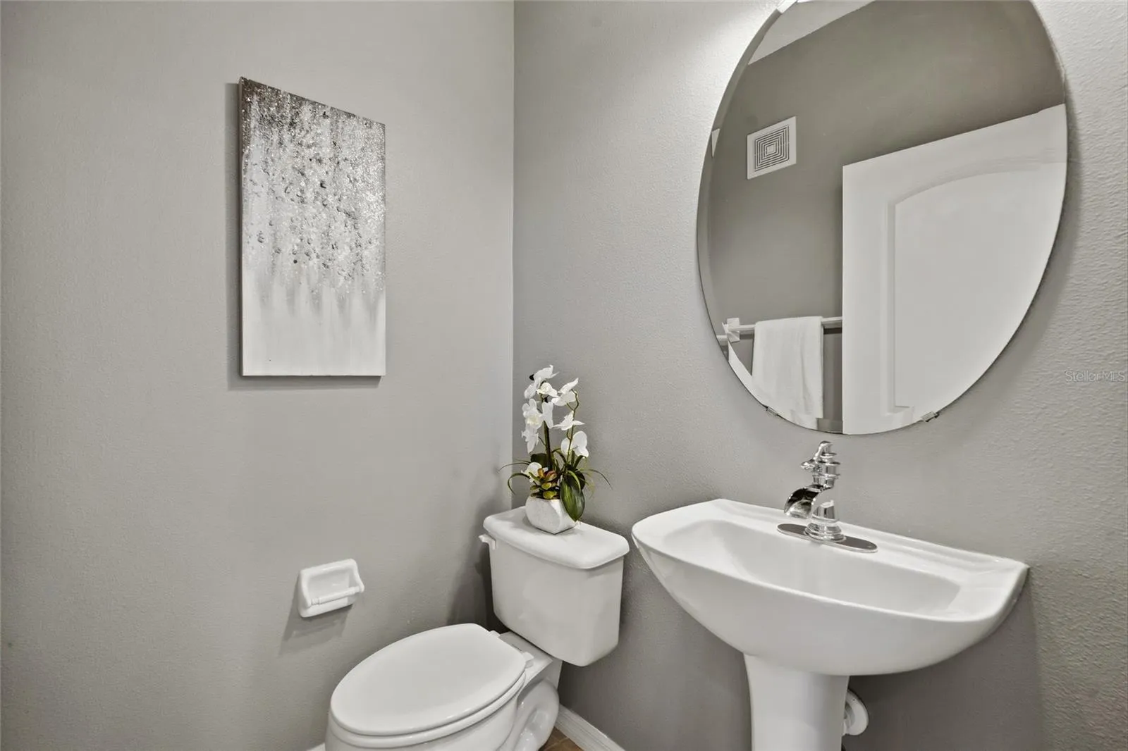 Powder Room Convenient main-level powder room with pedestal sink and contemporary round mirror.