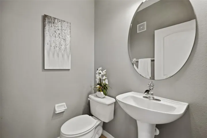 Powder Room Convenient main-level powder room with pedestal sink and contemporary round mirror.