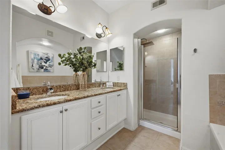 En-suite bath with dual-sink granite vanity and separate walk-in shower.