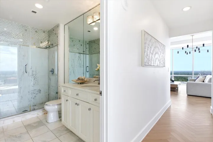 Full bath off the hallway, glass enclosed shower and single vanity.