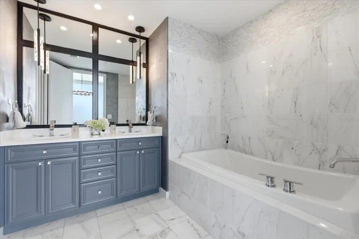 Double vanity and soaking tub are composed in a clean, balance layout, frame by stone and complemented by updated pendant lighting.