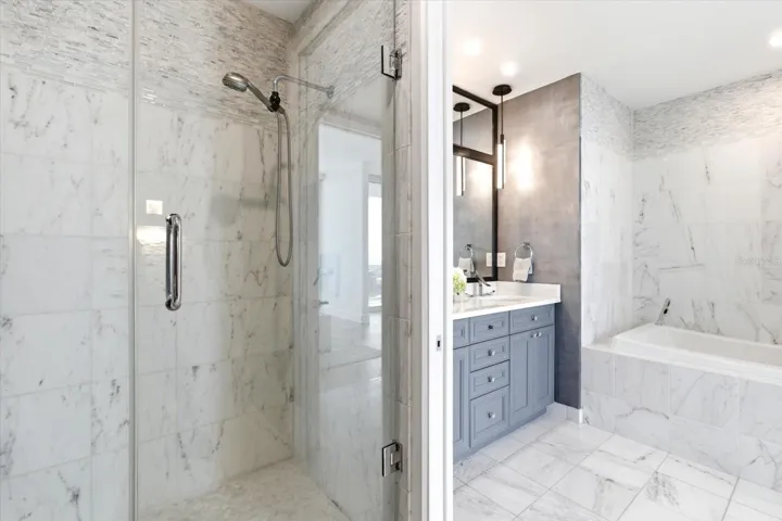 Shower and a discreetly positioned toilet are set opposite, with a pocket door separating them from the vanity and soaking tub.