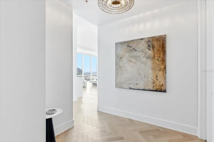 A refined entry sets the tone with herringbone wood flooring and sculptural lighting.
