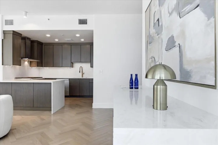Herringbone flooring establishes direction - guiding movement from entry through kitchen and living.