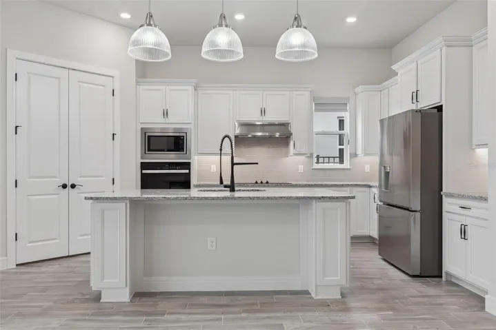 Oversized kitchen with granite countertops, double door walk-in pantry, Amazing LG Fridge and GE built in oven and microwave.  Lots of counterspace, drop down pendant lights and soft close cabinetry.