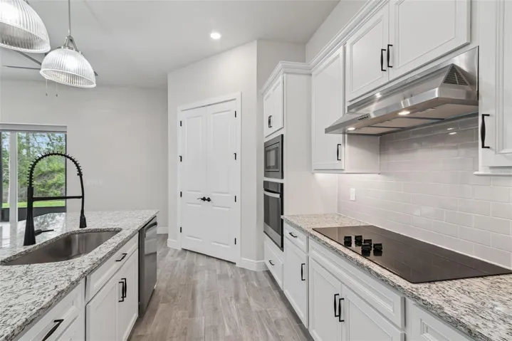 Vented cooking hood and moen fixtures are highlighted in the kitchen.