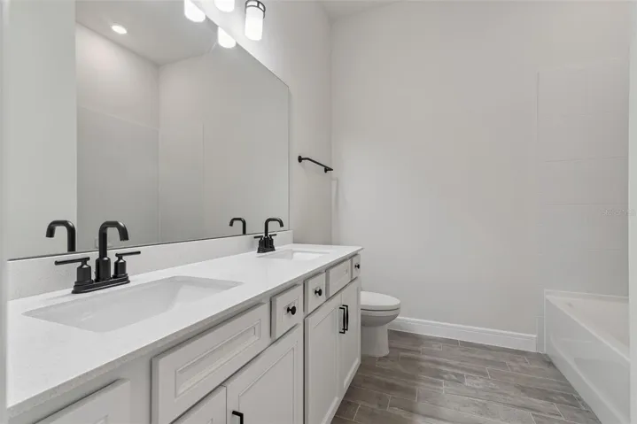 Shared bathroom has quartz countertops, soft close cabinets and moen fixtures and double sinks.