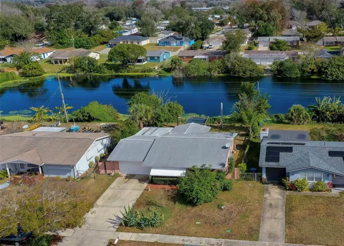 Aerial view showcasing the property’s placement along a tranquil lake. The water backdrop adds a peaceful outdoor feel and a standout sense of location.