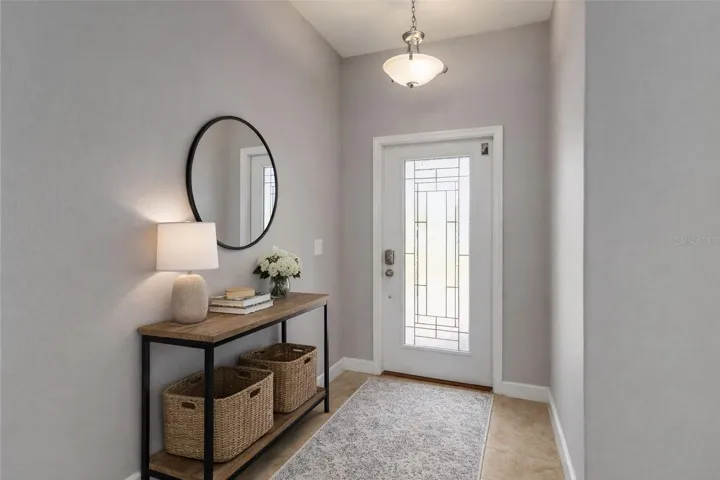 BRIGHT FOYER with HIGH CEILINGS and elegant GLASS FRONT DOOR.