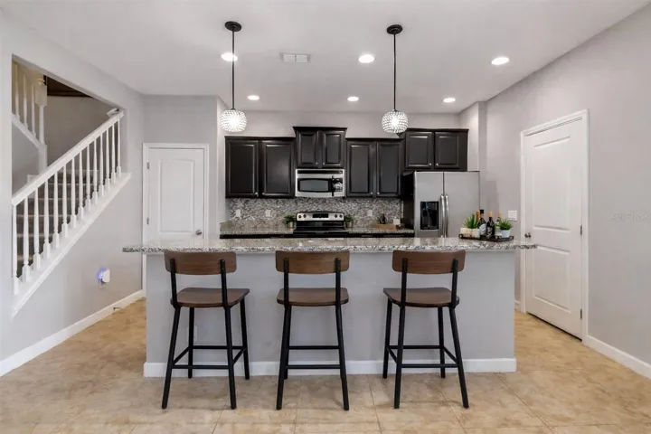 MODERN KITCHEN with GRANITE COUNTERS, STAINLESS STEEL APPLIANCES, and a LARGE BREAKFAST BAR perfect for entertaining.