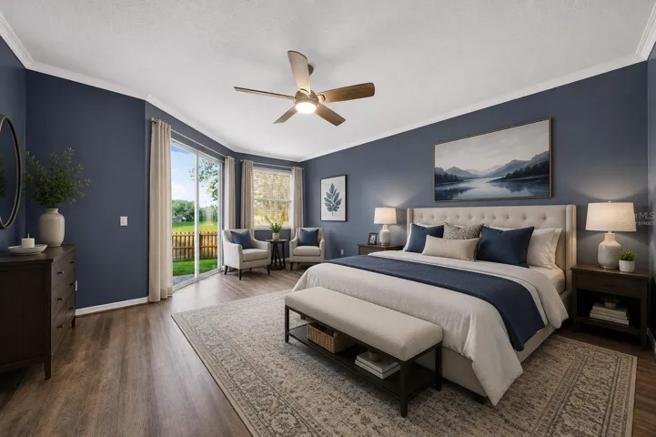 Virtually staged primary suite with sitting area and slider leading to the brick paver patio