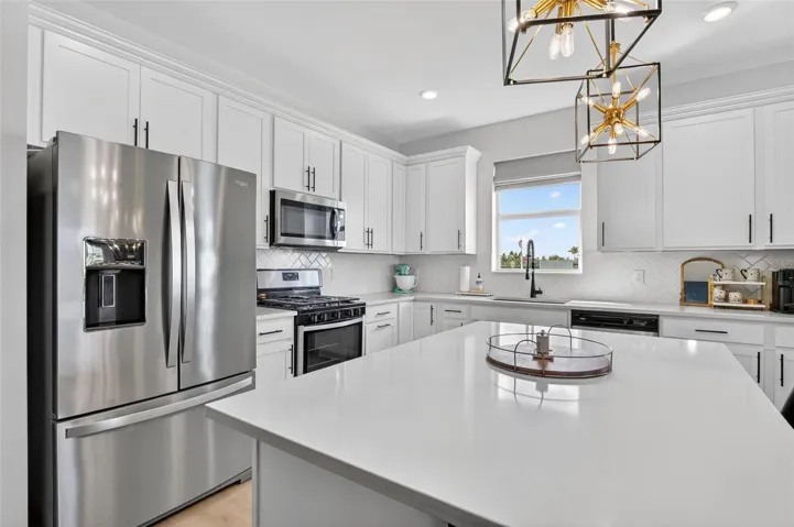 Kitchen featuring stainless steel appliances, white cabinetry backsplash, and recessed lighting