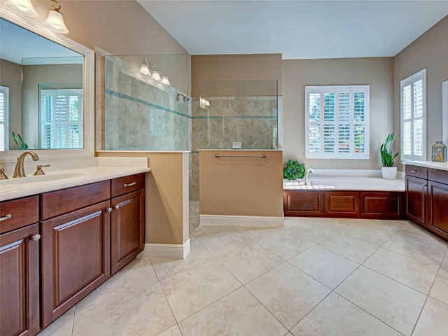 Elegant ensuite bathroom has dual, split vanities with lots of storage space, plantation shutters and over-sized, diagonal ceramic tiles.