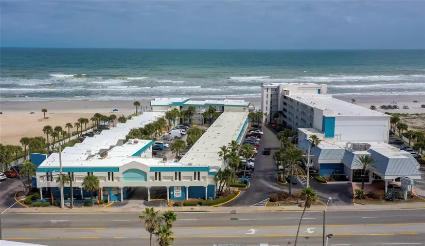 Oceanfront complex setting with direct beach access and a prime coastal location just steps from the sand. This elevated view highlights the community’s layout, parking, and proximity to the shoreline.