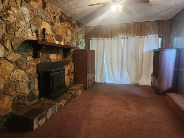 This stone wall Fireplace featuring Wood Burning Stove and Mantle makes this a cozy Family Room or another bedroom