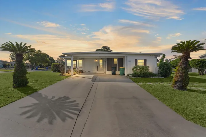 Lovely two bedroom, 2 bath manufactured home nestled on a corner homesite in Lake Frances Estates! Exterior photos showing the extra wide driveway and palm trees.