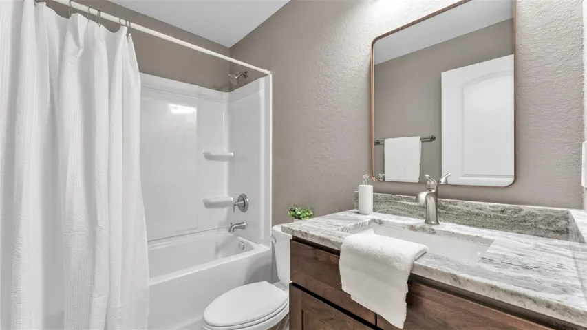 Hallway bathroom with granite counters and tub with shower