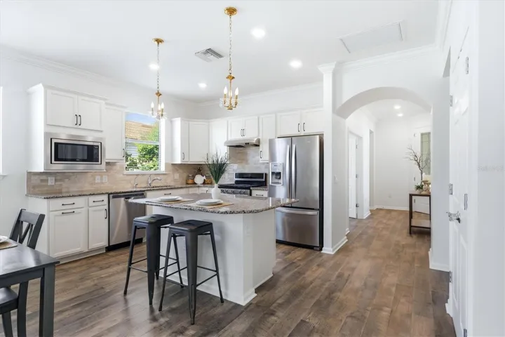 Stainless appliances, stone back splash, island with storage and room for stools.