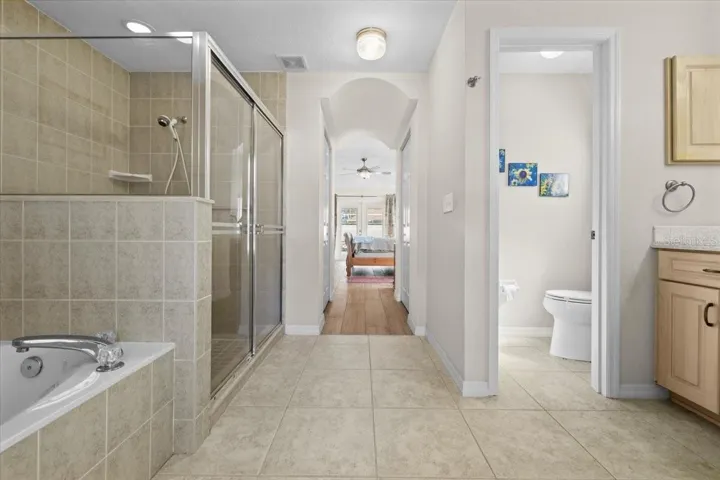 Expansive primary bath with soaking tub, separate shower, and private water closet, offering a well-designed layout for comfort and functionality.