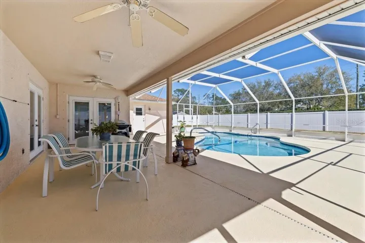 Expansive screened lanai with covered seating area and sparkling pool, offering the perfect setting for outdoor entertaining and relaxation.