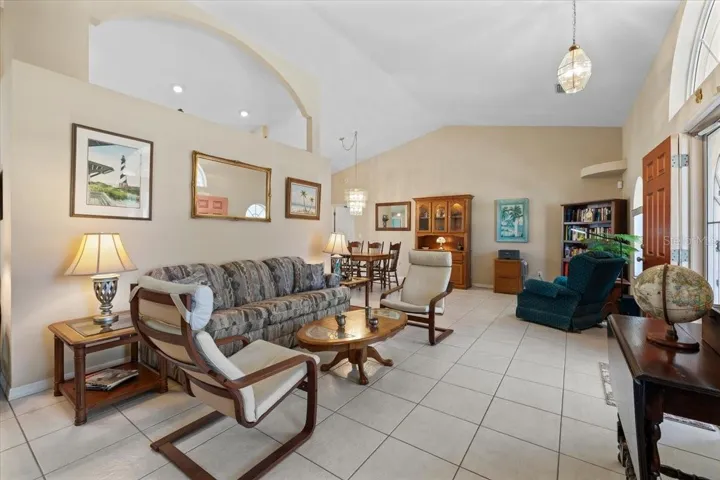 Bright and inviting living space featuring vaulted ceilings, tile flooring. Abundant natural light and architectural archways enhance the airy feel, perfect for both relaxing and entertaining.