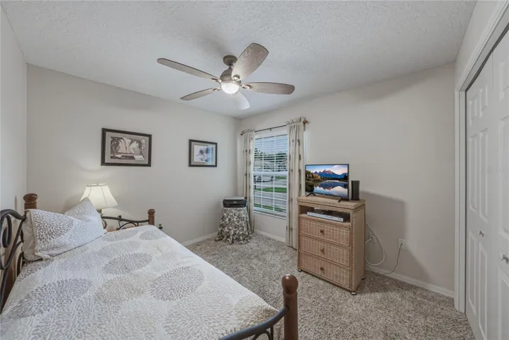 The guest bedroom has a ceiling fan with light and quality carpeting.