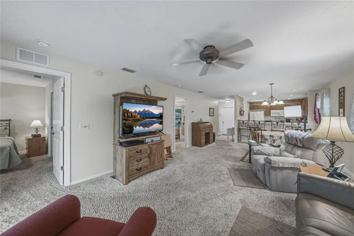 The combination living and dining room has a ceiling fan and quality carpeting.