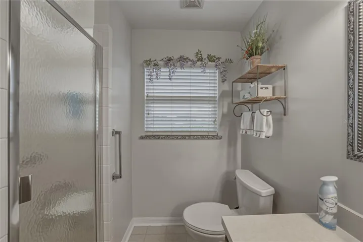 The primary bath has a stall shower with shower door, grab bar, and window.