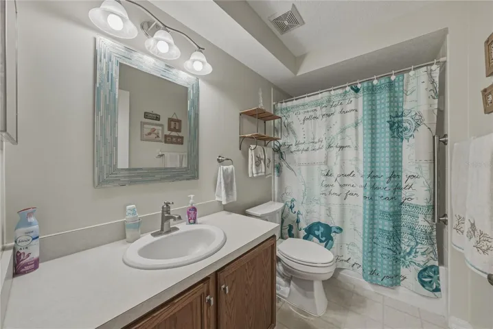 The guest bath has a tub and shower, upgraded lighting, elongated stool, and wood vanity.