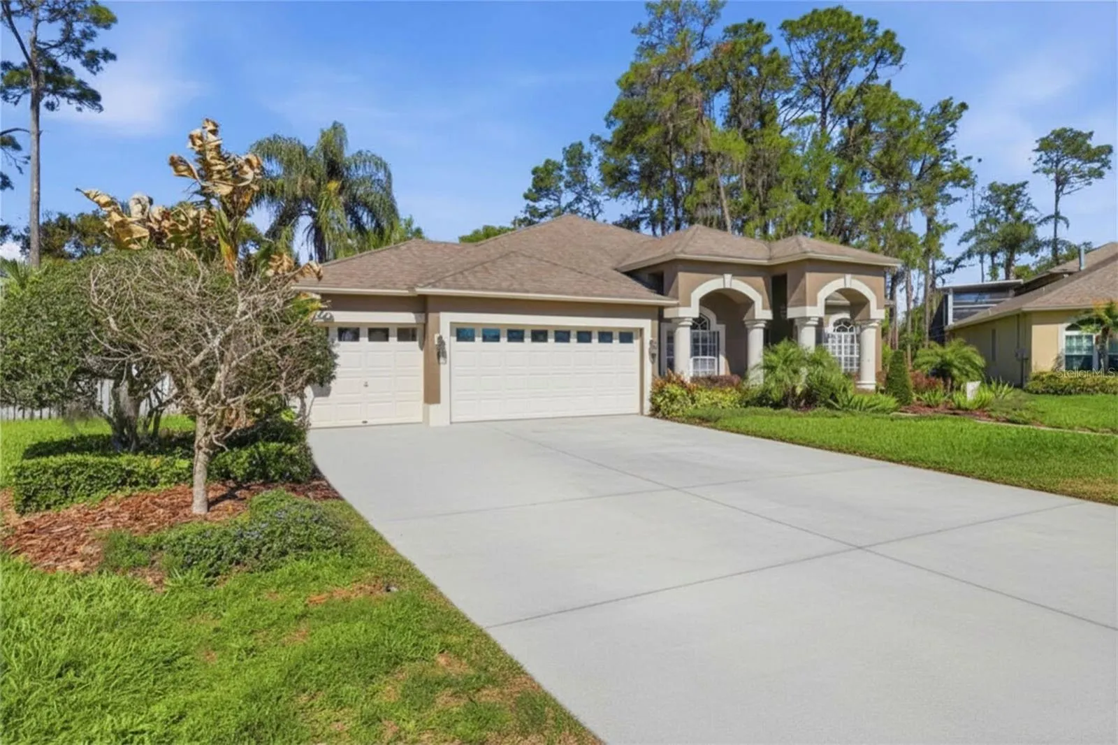 Inviting front exterior featuring an extended driveway, manicured landscaping, and a spacious three-car garage
