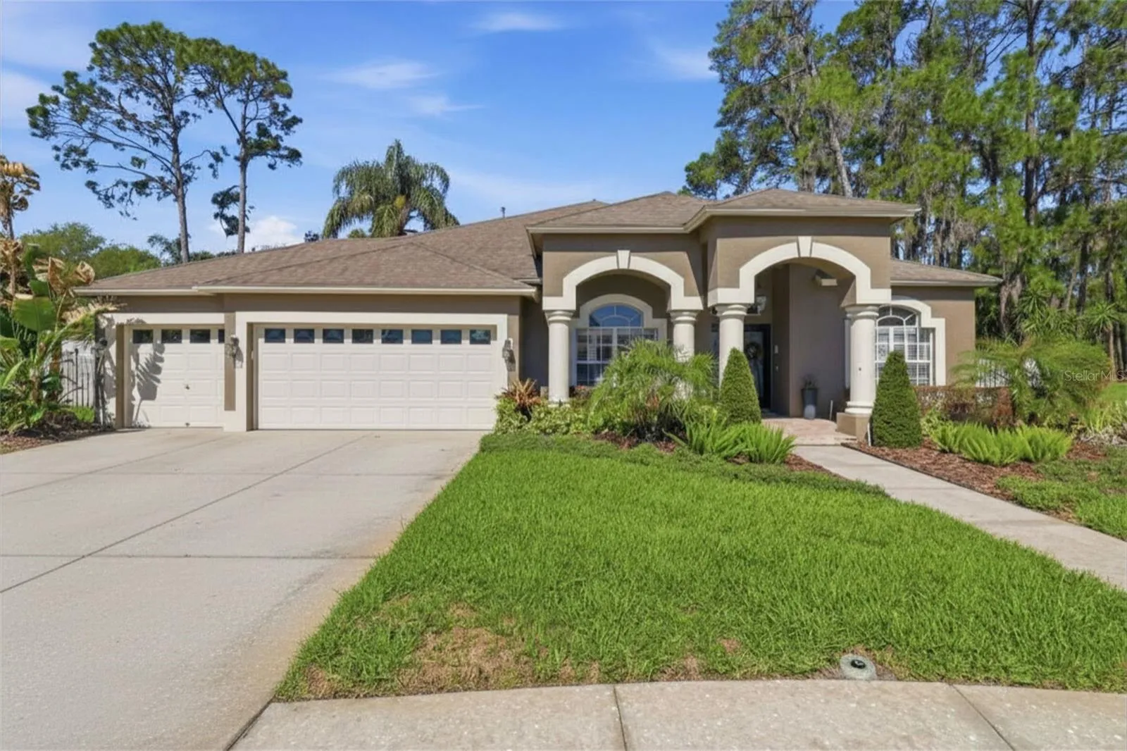 Stunning curb appeal with manicured landscaping, arched entryway, and oversized three-car garage