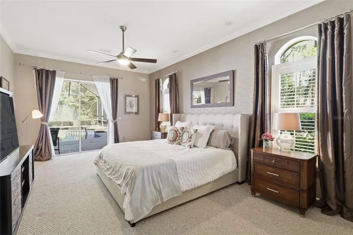 Primary suite with natural light, plantation shutters, and direct access to the pool area