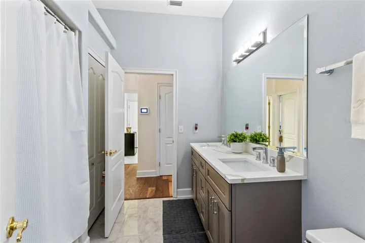 THE BATHROOM THAT BEDROOM 2 AND 3 SHARE HAVE THIS NEWLY RENOVATED BATHROOM WITH NEW TILE, DOUBLE SINK VANITY, LIGHTING AND FAUCETS.
