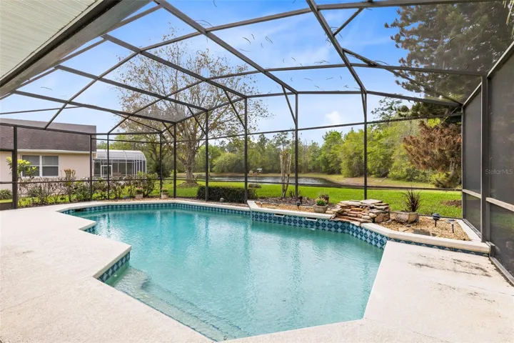 LARGE POOL WITH STEPS INTO THE SHALLOW END AND POND VIEW.