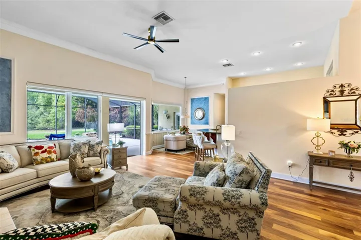 THE LARGE FAMILY ROOM WITH CROWN MOLDING, WOOD FLOORS FEATURES A LARGE SLIDING DOOR TO THE POOL.
