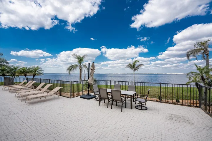 LOTS OF LOUNGE CHAIRS AND LARGE TABLE WITH THE LARGE UMBRELLA