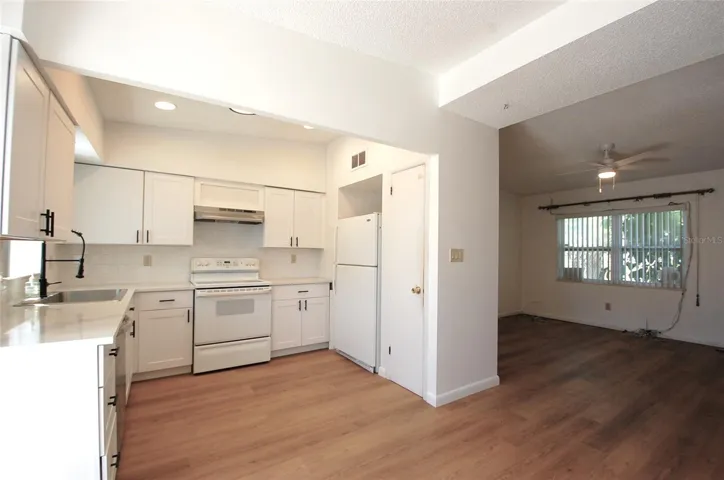Updated bright and light kitchen with white shaker-style cabinetry, subway tile backsplash, recessed lighting, new dish washer, window overlooking the pool and open to the dining room and living room.