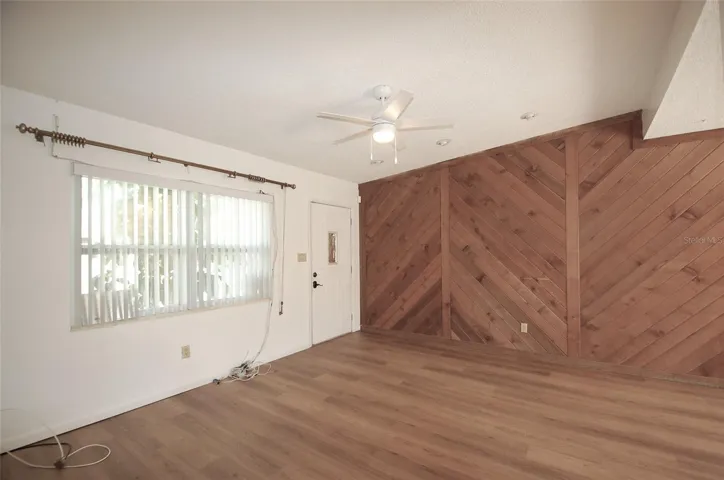 Living Room and Front entry doorway with large front facing window and cedar wood accent wall, new luxury vinyl flooring and vaulted ceilings.