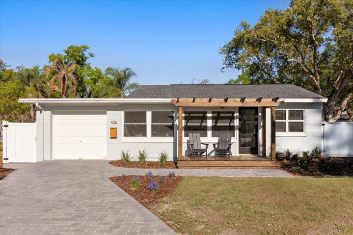 East facing view of home with pergola and paver driveway.
